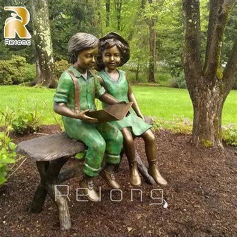 Colored outdoor statue of a child pressing their forehead on the hand of a seated elder