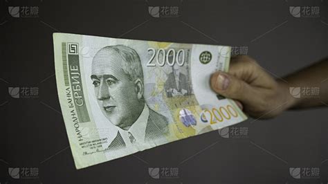 手中给钱——塞尔维亚2000第纳尔货币钞票。塞尔维亚货币RSD第纳尔现金。第纳尔和气候科学家米卢丁·