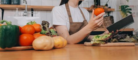 Köstliches Obst und Gemüse auf einem Tisch und eine Frau kocht Hausfrau ...