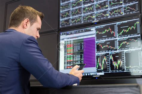 用手机交易股票的商人股票分析师在多个计算机屏幕上查看图表索引和数字股票交易员评估经济数据蓝色高清图片下载-正版图片505355182-摄图网