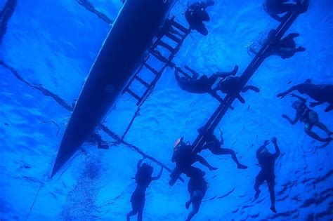 Pessoa em um barco com outra pessoa praticando snorkel ao lado do barco