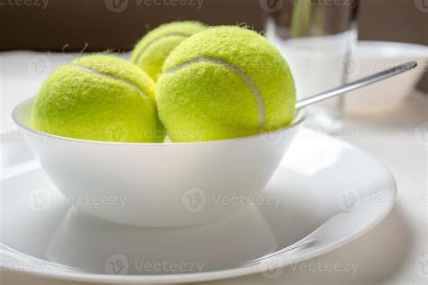 Yellow tennis balls in a bowl instead of ice cream, against a dark ...