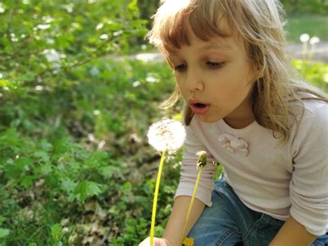 Śliczna dziewczynka wciąga powietrze w klatkę piersiową i zdmuchuje ...