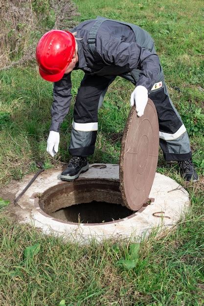 The communal worker opened the sewer hatch and looks inside inspection ...