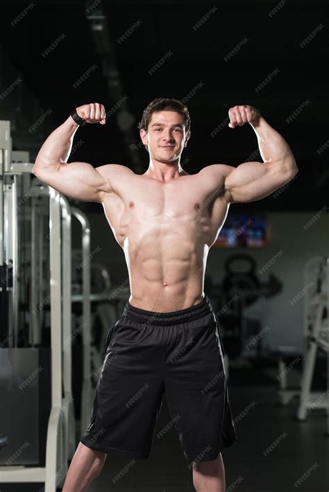 Bodybuilder Flexing Front Double Biceps Pose In Gym | Photo Premium