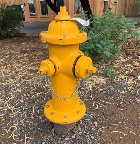 a yellow fire hydrant sitting on the side of a road next to a building