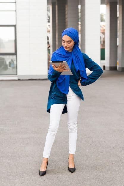 Classy teenager with hijab looking on her tablet | Free Photo