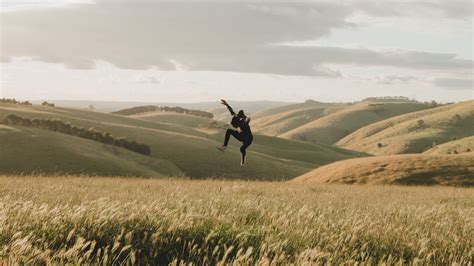 Download wallpaper 2560x1440 jump, levitation, silhouette, field, hills ...