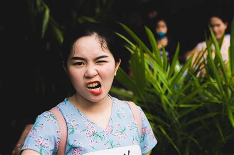 Portrait of smiling young woman making face against plants | Premium Photo