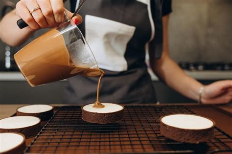 Smiling female confectioner pouring liquid chocolate gommage on biscuit ...