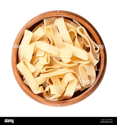 Sagnette, smooth ribbon pasta, in a wooden bowl. Uncooked, short thick ...