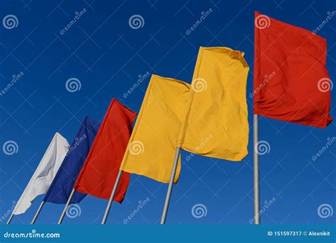 White, Blue, Red and Yellow Flags Develop in the Wind Against Sky Stock ...