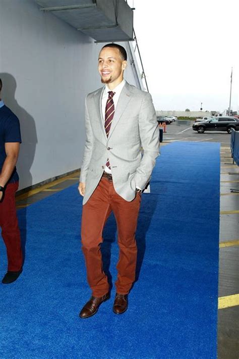 Stephen Curry wearing tan sweatshirt, khaki pants and white sneakers holding a multi-colored basketb