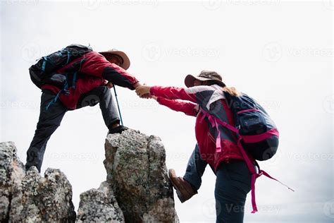 Person hike friends helping each other up a mountain. Man and woman ...