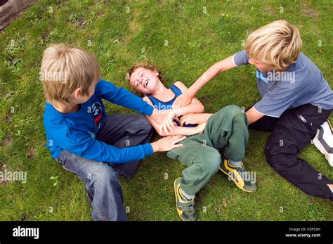 Two male children tickling another male child Stock Photo - Alamy