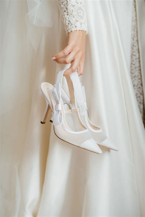the bride is holding her wedding shoes