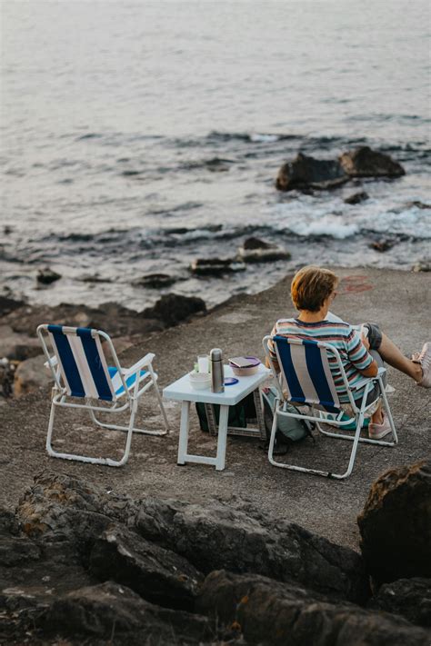Man Sitting on Chairs on Sea Shore · Free Stock Photo