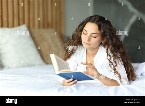Woman reading in The Ritz-Carlton bed at a hotel