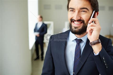 青年商人以其同事的办公室背景在电话上发言高清图片下载-正版图片507536021-摄图网