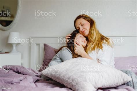 Mother and daughter cuddling on a bed in a kids room