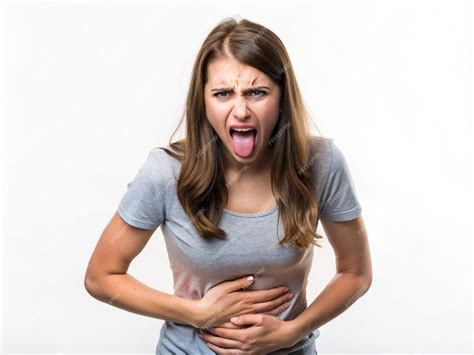 A young women making a disgusted face with her tongue out and hand on her stomach feeling queasy ...