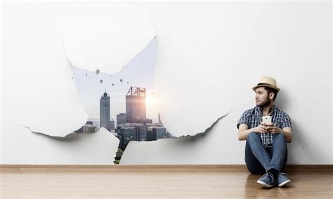 Young joyful man in casual clothes and a hat sitting on the floor ...