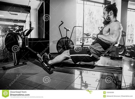 Muscular Fit Man Using Rowing Machine At Gym Stock Image - Image of ...