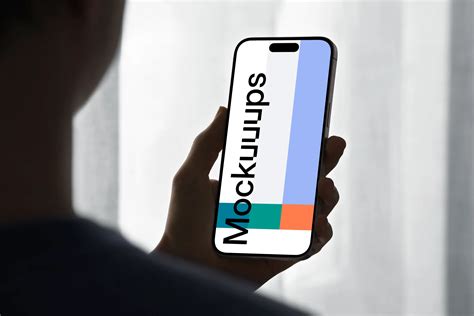 iPhone 15 Pro mockup in a male hand against soft backlight - Mockuuups ...