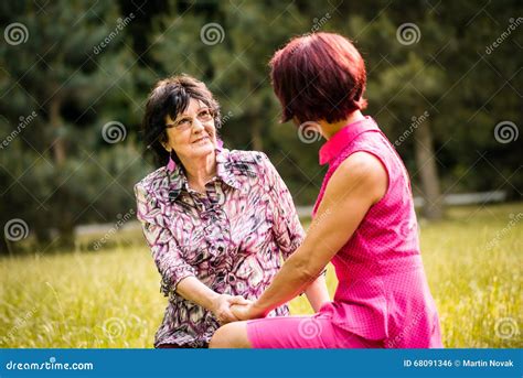 Adult daughter talking to her senior parents on a bench in a park