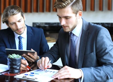 Two young businessmen analyzing financial document at meeting ...