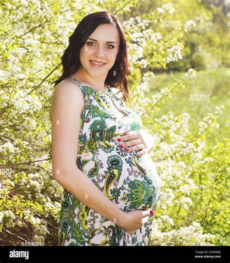 Portrait of beautiful pregnant woman in green dress in the flowering spring park Stock Photo - Alamy