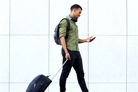 Young traveling man walking with suitcase and cellphone | Premium Photo