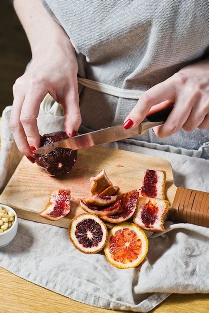 Chef cuts red oranges for salad with arugula. | Premium Photo
