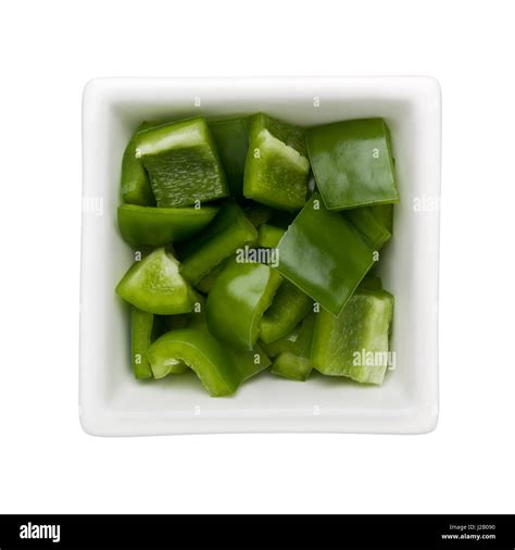 Diced green bell pepper in a square bowl isolated on white background ...