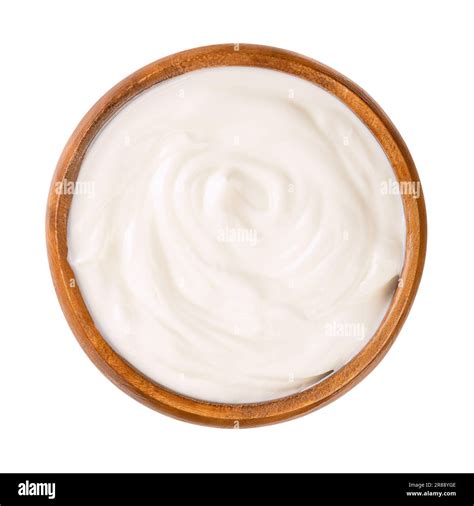 Cream yogurt, in a wooden bowl. Stirred yoghurt, also spelled yogourt or yoghourt, with ten ...