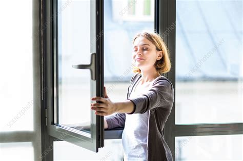 Woman opening window - Stock Image - C035/2747 - Science Photo Library