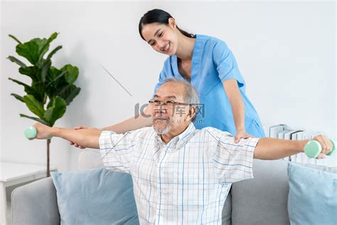 心满意足的老年患者在护理人员的帮助下进行物理治疗。高清摄影大图-千库网