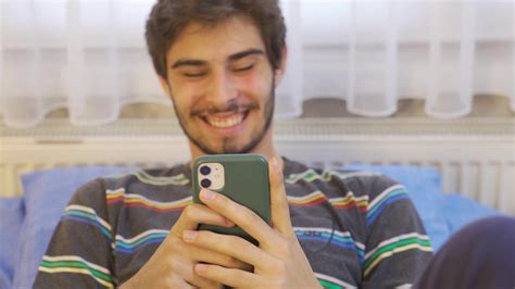 Young man watching funny videos on social media on his phone. Young man ...