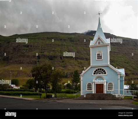 Blue Church at Seydisfjordur in East Iceland with cloudy mountains in ...