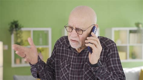Elderly man talking on the phone at home angry and aggressive. The old ...