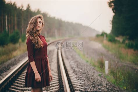 自然卷曲的漂亮女孩在铁路上的森林里享受大自然穿着勃艮第礼服的梦想家女士走在铁路上黎明时分在铁轨上的灵感女孩的女肖像秋天的高清图片下载-正版图片 ...
