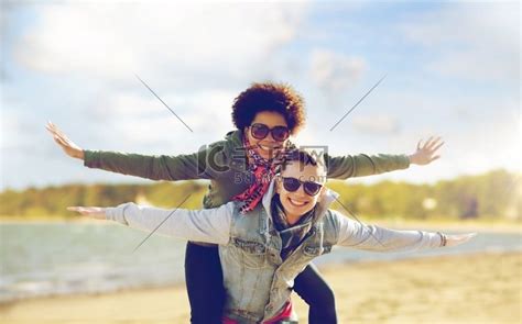 休闲、自由和人的概念-快乐的混血青少年夫妇戴着太阳镜在海滩背景下玩得开心。高清摄影大图-千库网