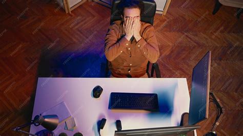 Top down view of software engineer putting face in hands in frustration ...