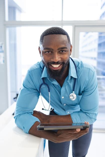Portrait of happy african american male doctor holding tablet at ...