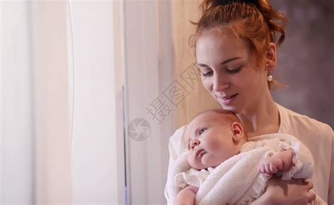 妈怀里抱着一个刚出生的婴儿女孩在窗前抱着一个婴儿母亲高清图片下载-正版图片506237906-摄图网