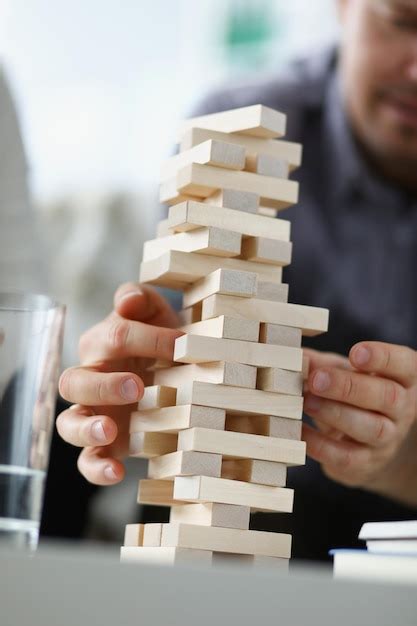 Young man removing wooden blocks from toy tower closeup | Premium Photo