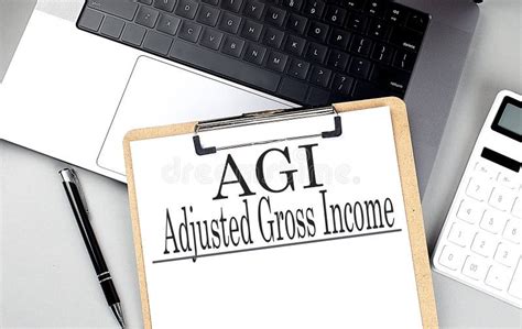 AGI -ADJUSTED GROSS INCOME Word on Clipboard on Laptop with Calculator ...
