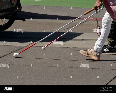 Two people with visual impairments use a white cane to help them ...