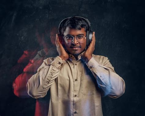Handsome indian man enjoying listening to music in wireless headphones ...