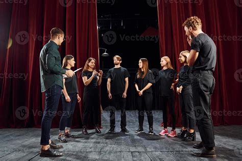 Working together. Group of actors in dark colored clothes on rehearsal ...